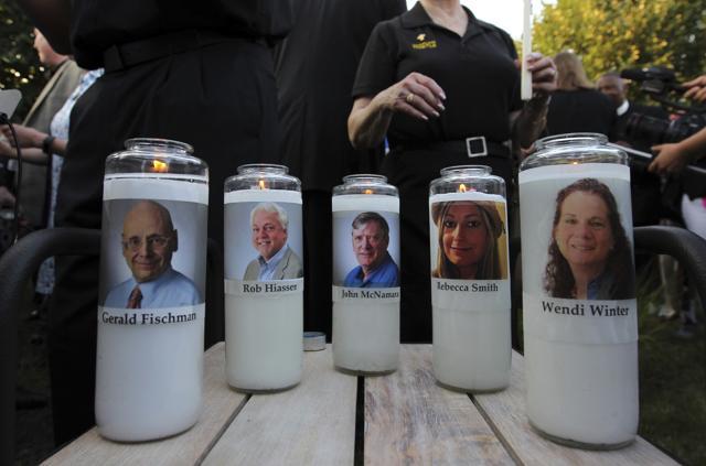 Photos of five journalists adorn candles during a vigil across the street from where they were slain in their newsroom in Annapolis. (AP Photo) Photos of five journalists adorn candles during a vigil across the street from where they were slain in their newsroom in Annapolis. (AP Photo)
