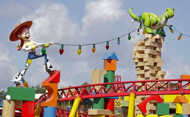 The character Jessie pulls on a string of giant lights tangled around Rex the dinosaur at Toy Story Land. (AP) The character Jessie pulls on a string of giant lights tangled around Rex the dinosaur at Toy Story Land. (AP)
