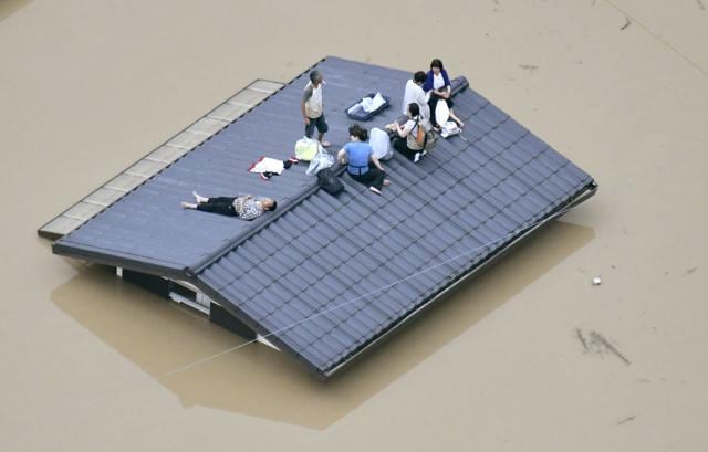 An aerial view shows local residents seen on the roof of submerged house at a flooded area as they wait for a rescue in Kurashiki, southern Japan on July 7. (Kyodo/via REUTERS ) An aerial view shows local residents seen on the roof of submerged house at a flooded area as they wait for a rescue in Kurashiki, southern Japan on July 7. (Kyodo/via REUTERS )