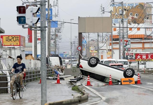 An overturned car remains on a street after heavy rain in Ozu, Ehime Prefecture, Japan. (Kyodo/via Reuters)