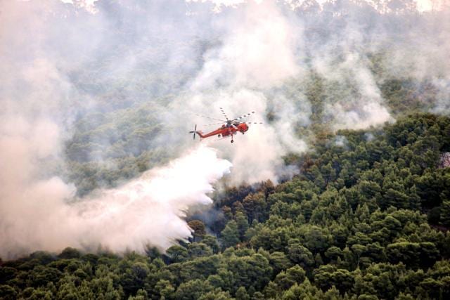 A firefighting helicopter drops water to extinguish flames during a wildfire at the village of Kineta, near Athen. (AFP Photo) A firefighting helicopter drops water to extinguish flames during a wildfire at the village of Kineta, near Athen. (AFP Photo)