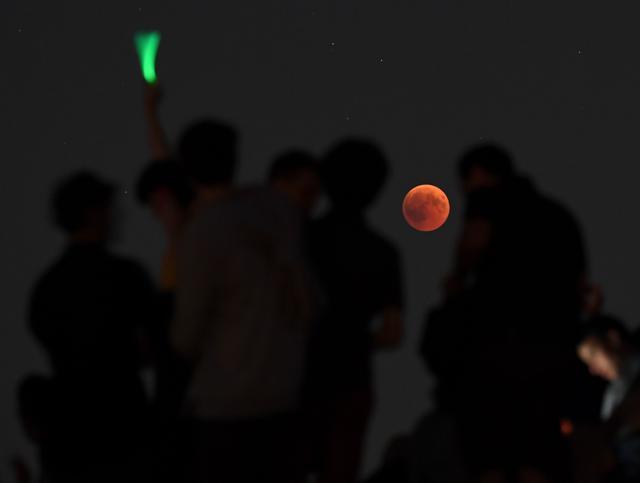 People gathered to watch the total lunar eclipse in the Olympic park in Munich, southern Germany, on July 27, 2018. (AFP) People gathered to watch the total lunar eclipse in the Olympic park in Munich, southern Germany, on July 27, 2018. (AFP)