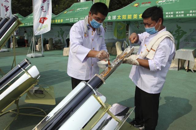 Chefs prepare to cook skewers of meat in a solar cooker. (AP) Chefs prepare to cook skewers of meat in a solar cooker. (AP)