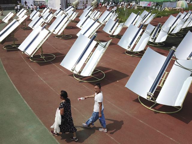 Women walk past rows of solar cookers. (AP) Women walk past rows of solar cookers. (AP)