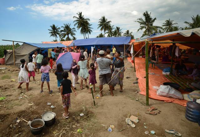 Children raise their hands as a helicopter flies overhead the evacuation tents in Kayangan, in northern Lombok island on August 9, 2018 following the August 5 earthquake. (AFP) Children raise their hands as a helicopter flies overhead the evacuation tents in Kayangan, in northern Lombok island on August 9, 2018 following the August 5 earthquake. (AFP)