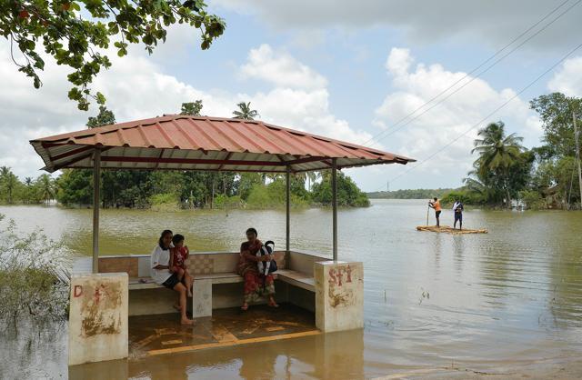 Residents of Pandanad sit in a bus stand surrounded by flood waters from the overflowing Pampa river while raft is pictured near them transported people in Pandanad of Alappuzha district on August 21. (AFP Photo) Residents of Pandanad sit in a bus stand surrounded by flood waters from the overflowing Pampa river while raft is pictured near them transported people in Pandanad of Alappuzha district on August 21. (AFP Photo)