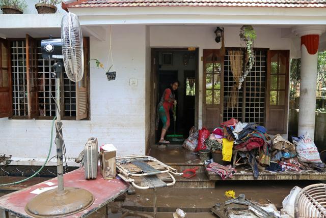 A woman cleans the mud from the entrance of her house following floods in Paravur in the southern state of Kerala on August 21. (REUTERS) A woman cleans the mud from the entrance of her house following floods in Paravur in the southern state of Kerala on August 21. (REUTERS)