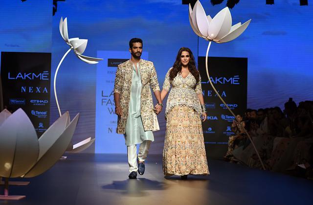 Bollywood actress Neha Dhupia and her actor husband Angad Bedi showcases a creation by designer Payal Singhal at the Lakme Fashion Week (LFW) Winter/Festive 2018 in Mumbai on August 25. (AFP)