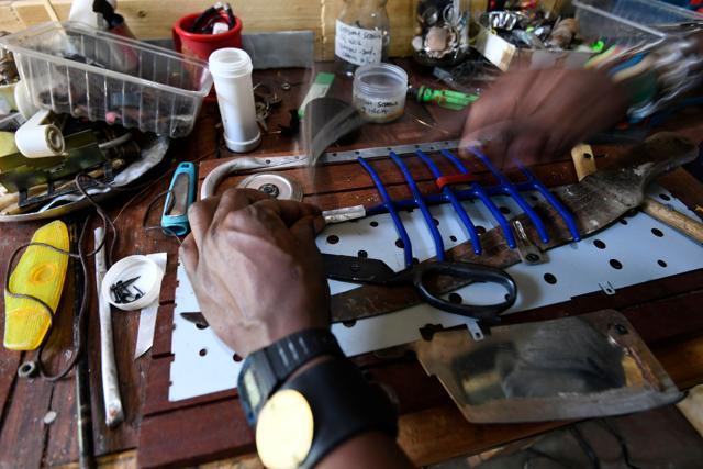 Evans Ngure works on a sculpture, a fantastical fish fabricated from found objects: wooden spoons, broken scissors and an old machete. (AFP) Evans Ngure works on a sculpture, a fantastical fish fabricated from found objects: wooden spoons, broken scissors and an old machete. (AFP)