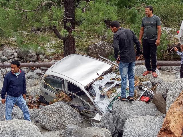 Locals inspect a damaged car washed ashore due to incessant rains, at Palampur approximately 45km from Dharamshala, on September 24, 2018. (PTI) Locals inspect a damaged car washed ashore due to incessant rains, at Palampur approximately 45km from Dharamshala, on September 24, 2018. (PTI)