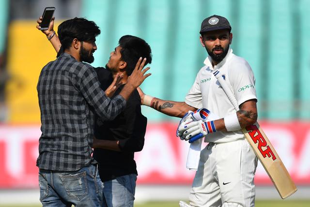 Indian cricket captain Virat Kohli (R) looks on as pitch invaders try to click a selfie with him. (AFP)