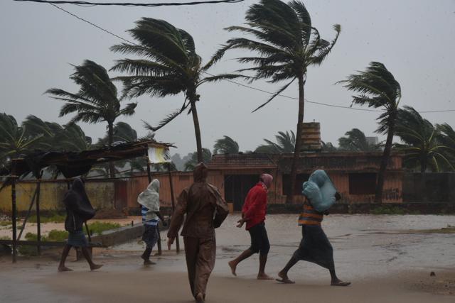 People walk against the wind in Odisha’s Gopalpur in Ganjam district after Cyclone Titli made landfall, on Thursday. (Arabinda Mahapatra/HT Photo)