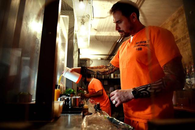 A mixologist dressed in prison clothing makes cocktails for guests. (AFP) A mixologist dressed in prison clothing makes cocktails for guests. (AFP)