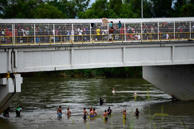 Honduran migrants heading in a caravan to the US, wait to help fellow men get down to the Suchiate River from the Guatemala-Mexico international border bridge, in Ciudad Hidalgo. (AFP Photo) Honduran migrants heading in a caravan to the US, wait to help fellow men get down to the Suchiate River from the Guatemala-Mexico international border bridge, in Ciudad Hidalgo. (AFP Photo)