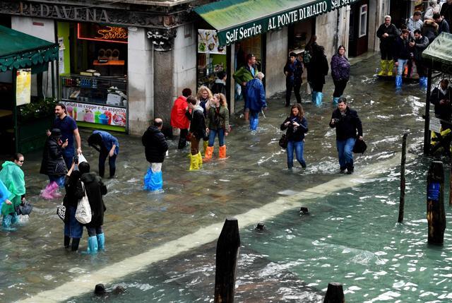 Tourists walk in the flooded street near Rialto Bridge during a acqua-alta (high-water) alert in Venice on October 29. (AFP Photo)