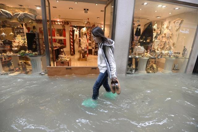 A woman walks in a flooded street of Venice, Italy on October 29. (AP Photo)