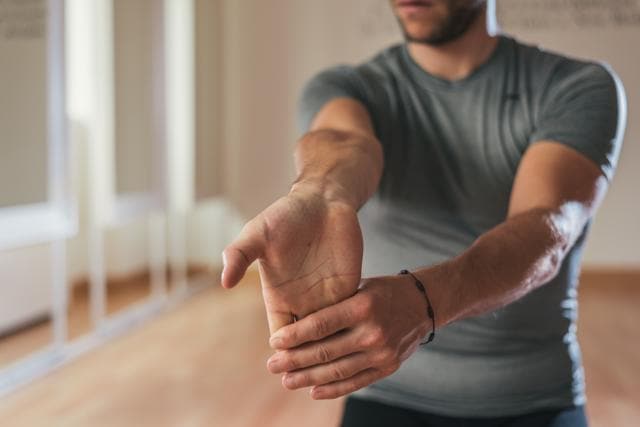 Sit in a comfortable chair, hold your arm straight in front of you, with the palm up towards the ceiling. With the other hand grab the palm and pull towards you Sit in a comfortable chair, hold your arm straight in front of you, with the palm up towards the ceiling. With the other hand grab the palm and pull towards you