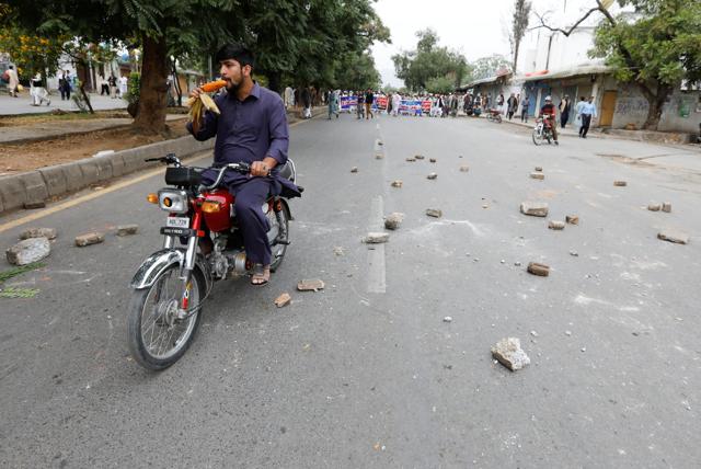 A man eats a corn cob while driving along a road where Supporters of Muslim Student Organisation (MSO) protest after the Supreme Court overturned the conviction of a Christian woman sentenced to death for blasphemy against Islam. (REUTERS) A man eats a corn cob while driving along a road where Supporters of Muslim Student Organisation (MSO) protest after the Supreme Court overturned the conviction of a Christian woman sentenced to death for blasphemy against Islam. (REUTERS)