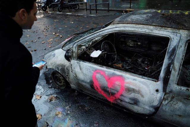 A man looks at a burned car in a street in Paris after clashes during a protest of Yellow Vests against rising oil prices and living costs. (AFP)