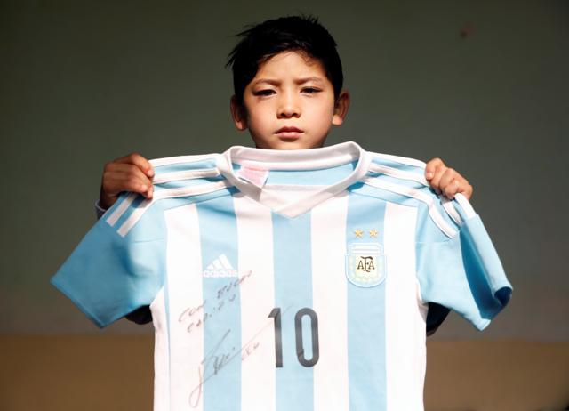Murtaza Ahmadi holds a T-shirt signed by Barcelona star Lionel Messi at his house in Kabul, Afghanistan. (REUTERS)