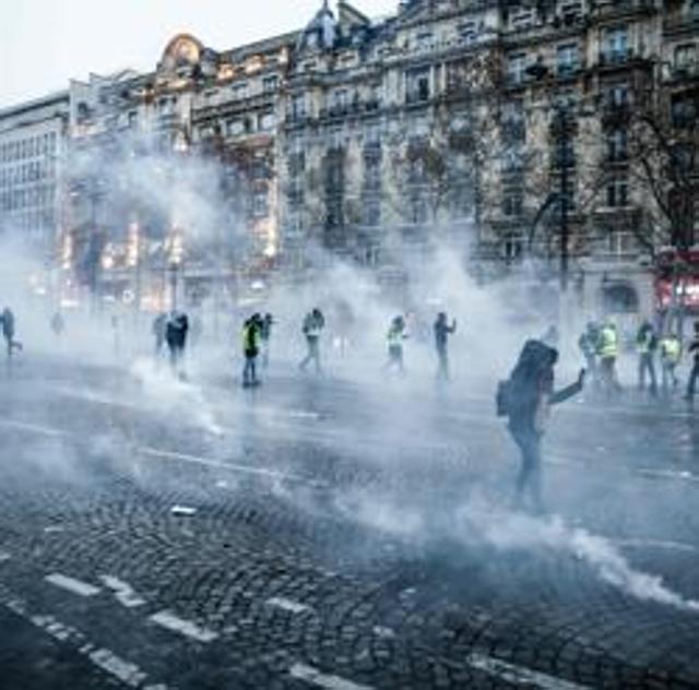 Protesters wearing yellow vests (gilets jaunes) stand amid smoke of tear gas during a demonstration against rising costs of living they blame on high taxes on the Champs-Elysees avenue in Paris, on December 15, 2018. - The "Yellow Vests" (Gilets Jaunes) movement in France originally started as a protest about planned fuel hikes but has morphed into a mass protest against President's policies and top-down style of governing. (Photo by Abdul ABEISSA / AFP) (AFP) Protesters wearing yellow vests (gilets jaunes) stand amid smoke of tear gas during a demonstration against rising costs of living they blame on high taxes on the Champs-Elysees avenue in Paris, on December 15, 2018. - The "Yellow Vests" (Gilets Jaunes) movement in France originally started as a protest about planned fuel hikes but has morphed into a mass protest against President's policies and top-down style of governing. (Photo by Abdul ABEISSA / AFP) (AFP)
