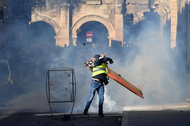 Masked demonstrators gesture amid smoke of teargas canisters launched by anti-riot police in a street heading to the Arena of Nimes in background during an anti-government demonstration called by the Yellow Vests movement, in Nimes. (AFP Photo) Masked demonstrators gesture amid smoke of teargas canisters launched by anti-riot police in a street heading to the Arena of Nimes in background during an anti-government demonstration called by the Yellow Vests movement, in Nimes. (AFP Photo)