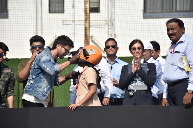 Shahid Kapoor helps a young fan wear a helmet. Shahid Kapoor helps a young fan wear a helmet.