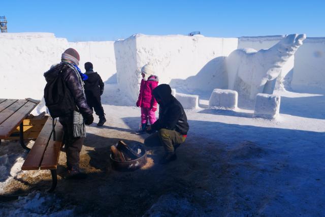 A family rests and warms near a firepit located within the snow. (AFP) A family rests and warms near a firepit located within the snow. (AFP)