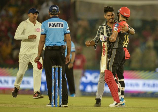 A fan of Royal Challengers Bangalore (RCB) cricketer Virat Kohli (R) hugs him as he runs on the pitch. (AFP)