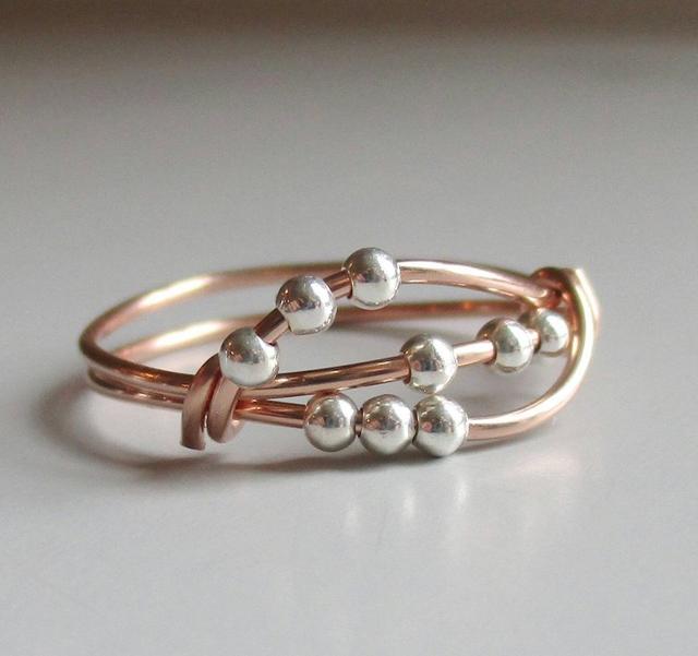 A Patti + Ricky fidget ring with movable beads and interlocking rings. A Patti + Ricky fidget ring with movable beads and interlocking rings.