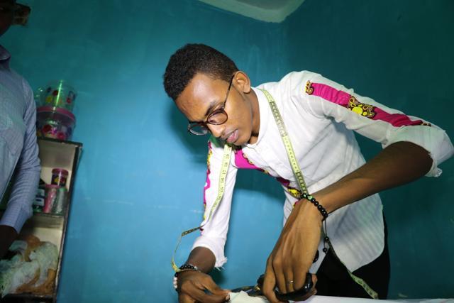 Abdishakur Abdirahman Adam, 19 years old, secondary school student and fashion designer for women and men, cuts fabrics, on November 4, 2018, in Mogadishu.(Photo by Abdi HAJJI HUSSEIN / AFP) (AFP) Abdishakur Abdirahman Adam, 19 years old, secondary school student and fashion designer for women and men, cuts fabrics, on November 4, 2018, in Mogadishu.(Photo by Abdi HAJJI HUSSEIN / AFP) (AFP)