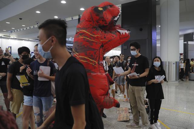 A person wearing a dinosaur costume joins protesters in a second day of sit-in protest at the airport in Hong Kong. (AP) A person wearing a dinosaur costume joins protesters in a second day of sit-in protest at the airport in Hong Kong. (AP)