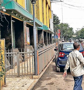 The footpath outside the Dorabjee department store in Camp has a gate with a lock. The pathway is not accessible to pedestrians. Illegal hawkers have also encroached MG road. (Shankar Narayan/HT PHOTO)