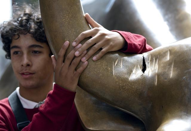 A visitor at the popular lower Manhattan sculpture "Charging Bull" poses for a photo next to the sculpture's damaged horn. (AP) A visitor at the popular lower Manhattan sculpture "Charging Bull" poses for a photo next to the sculpture's damaged horn. (AP)