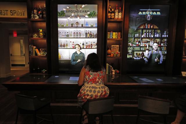 A visitor sits at a mock bar and watches interactive virtual bartenders during a media preview for the Sazerac house. (AP Photo/Gerald Herbert) (AP) A visitor sits at a mock bar and watches interactive virtual bartenders during a media preview for the Sazerac house. (AP Photo/Gerald Herbert) (AP)