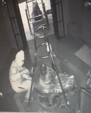 A CCTV grab of a burglar using pliers to remove the silver coating from a shivling. (HT PHOTO) A CCTV grab of a burglar using pliers to remove the silver coating from a shivling. (HT PHOTO)