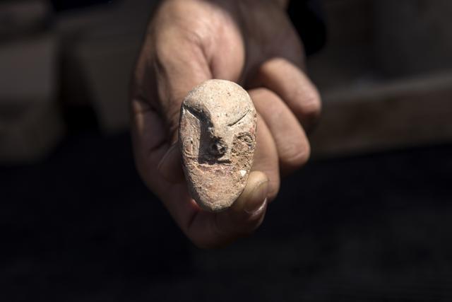 An archeologists shows a figurine found at a large, 5,000-year-old city in northern Israel. Israel's Antiquities Authority said Sunday the ancient city was discovered during preparations for a new highway interchange near Harish, a town roughly 50 kilometers (30 miles) north of Tel Aviv, Sunday, Oct. 6, 2019. (AP Photo/Tsafrir Abayov) (AP)