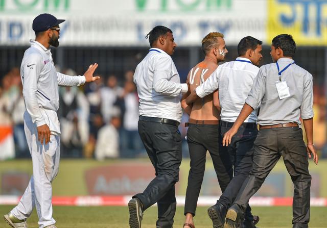 Indore: Indian cricket captain Virat Kohli (L) looks on as security personnel take away a pitch invader. (PTI) Indore: Indian cricket captain Virat Kohli (L) looks on as security personnel take away a pitch invader. (PTI)