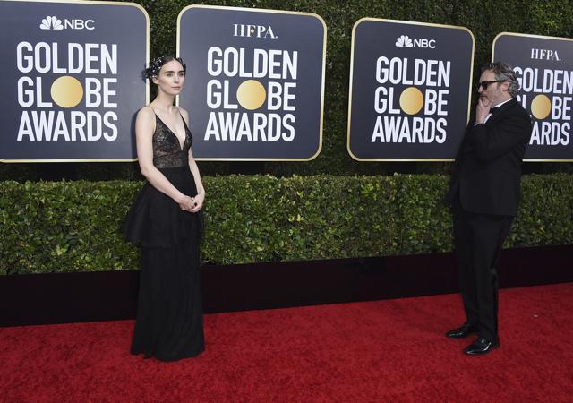 Rooney Mara, left, walks on the red carpet as Joaquin Phoenix looks on. (Jordan Strauss/Invision/AP)
