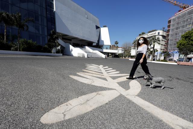 A woman wearing a protective face mask walks her dog past a Palme d'Or symbol on the pavement near the Festival palace on the Croisette in Cannes where the Cannes Film Festival and the Cannes Lions take place, as a lockdown is imposed to slow the rate of the coronavirus disease (Covid-19), in France, March 18, 2020. (REUTERS) A woman wearing a protective face mask walks her dog past a Palme d'Or symbol on the pavement near the Festival palace on the Croisette in Cannes where the Cannes Film Festival and the Cannes Lions take place, as a lockdown is imposed to slow the rate of the coronavirus disease (Covid-19), in France, March 18, 2020. (REUTERS)