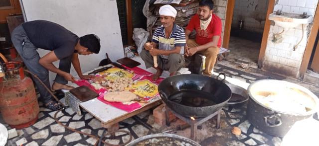 The image shows men preparing food to be distributed among people.