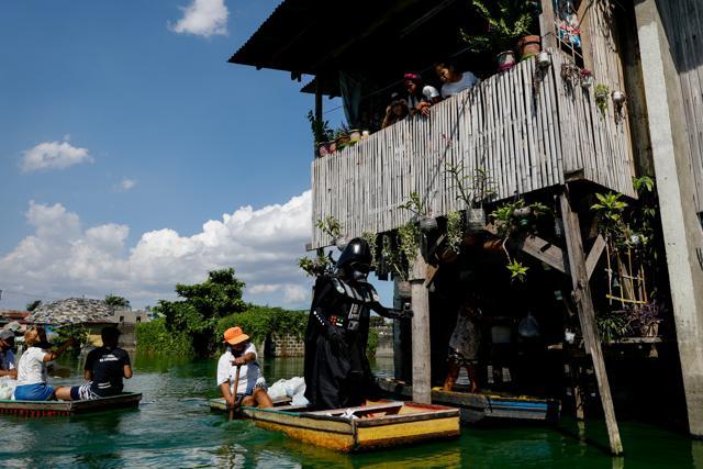 A village officer dressed as the Star Wars character Darth Vader rides a small boat to deliver relief goods. (REUTERS) A village officer dressed as the Star Wars character Darth Vader rides a small boat to deliver relief goods. (REUTERS)
