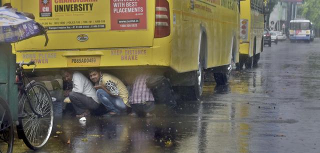 Migrants taking cover under a bus during heavy rain in Ludhiana on Thursday. (Gurpreet Singh/HT) Migrants taking cover under a bus during heavy rain in Ludhiana on Thursday. (Gurpreet Singh/HT)