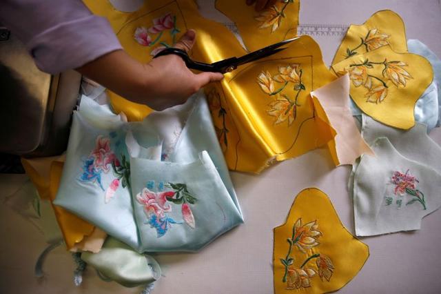 A worker cuts patterns off a silk cloth for making face masks designed by Zhou Li, at a studio in Beijing, following the novel coronavirus disease (COVID-19) outbreak, China May 17, 2020. Picture taken May 17, 2020. REUTERS/Tingshu Wang (REUTERS)