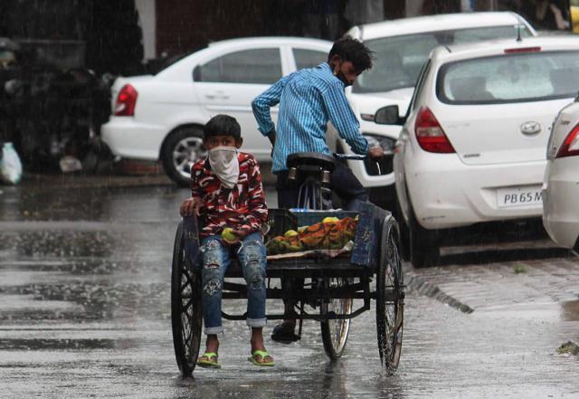 A fruit vendor makes his way through traffic amid the rain in Mohali on Friday. (Gurminder Singh/HT ) A fruit vendor makes his way through traffic amid the rain in Mohali on Friday. (Gurminder Singh/HT )