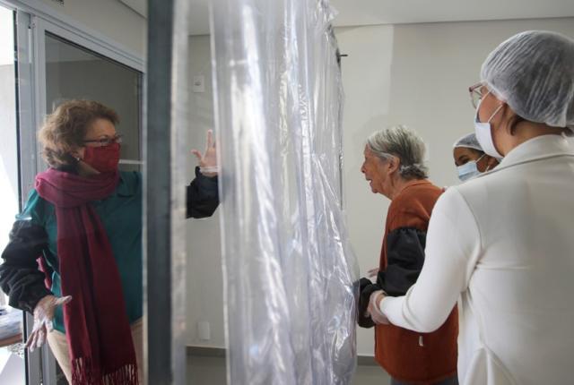 Dircyree Villas Boas waves to her mother Dirce Villas Boas, 93, through a plastic curtain at the 3i Bem-Estar - Residencial Senior nursing home. (Reuters) Dircyree Villas Boas waves to her mother Dirce Villas Boas, 93, through a plastic curtain at the 3i Bem-Estar - Residencial Senior nursing home. (Reuters)