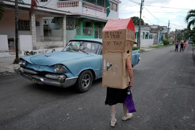 Retired nurse Feridia Rojas, 82, walks past a vintage car as she wears cardboard. (REUTERS) Retired nurse Feridia Rojas, 82, walks past a vintage car as she wears cardboard. (REUTERS)