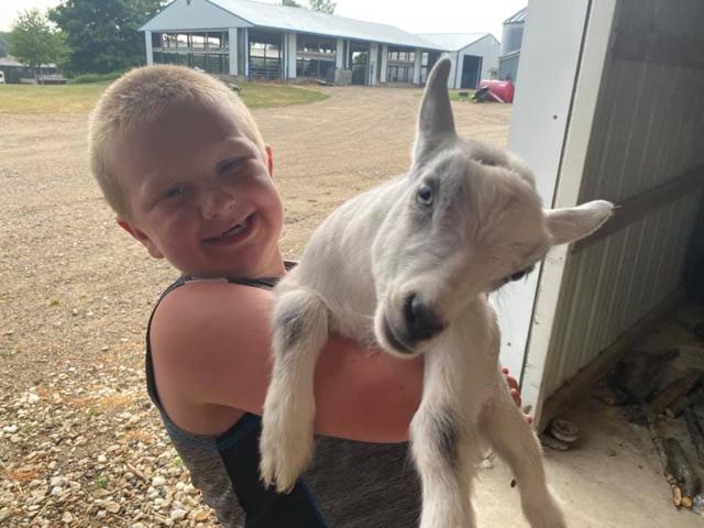 The image shows a happy kid holding a goat. (Facebook/@MOOville) The image shows a happy kid holding a goat. (Facebook/@MOOville)