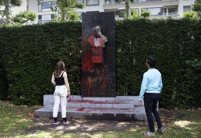In this Friday, June 19, 2020 file photo, a couple stop to look at a bust of Belgium's King Leopold II, which has been damaged by red paint, graffiti and cement, at a park in Ghent, Belgium. (AP Photo/Virginia Mayo, File) In this Friday, June 19, 2020 file photo, a couple stop to look at a bust of Belgium's King Leopold II, which has been damaged by red paint, graffiti and cement, at a park in Ghent, Belgium. (AP Photo/Virginia Mayo, File)