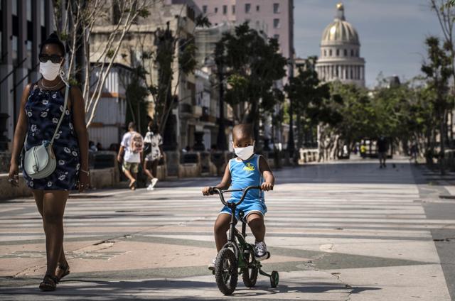 A woman accompanies a child on a bicycle, both wearing protective face masks as a precaution amid the spread of the new coronavirus, in Havana, Cuba, Friday, July 3, 2020. (AP) A woman accompanies a child on a bicycle, both wearing protective face masks as a precaution amid the spread of the new coronavirus, in Havana, Cuba, Friday, July 3, 2020. (AP)